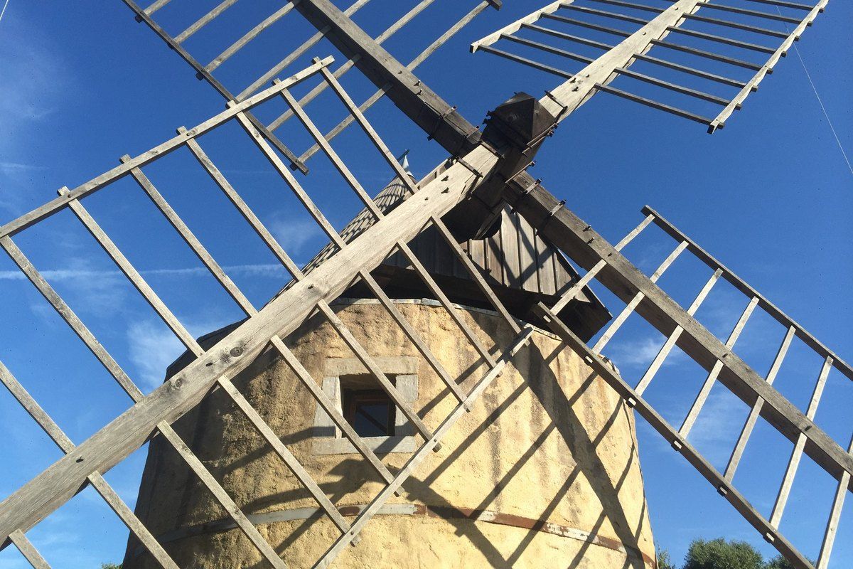 The wooden sails of the Moulin de Paillas against a blue sky