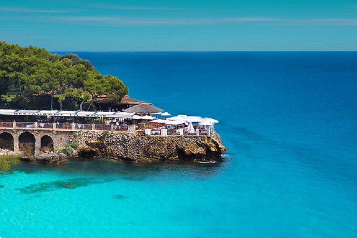 The open-air terrace of Club La Vigie on its rocky point above turquoise water at Monte-Carlo Beach