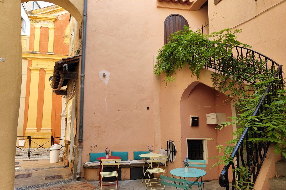 Café tables and turquoise chairs in a small square of Roquebrune village outside the Grimaldi Café