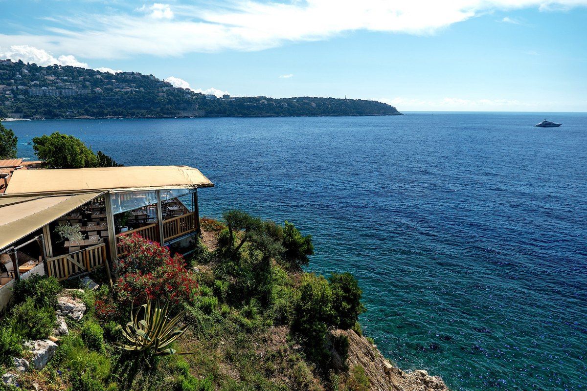 The terrace of La Différance on a wooded slope above the blue sea and Cap Martin