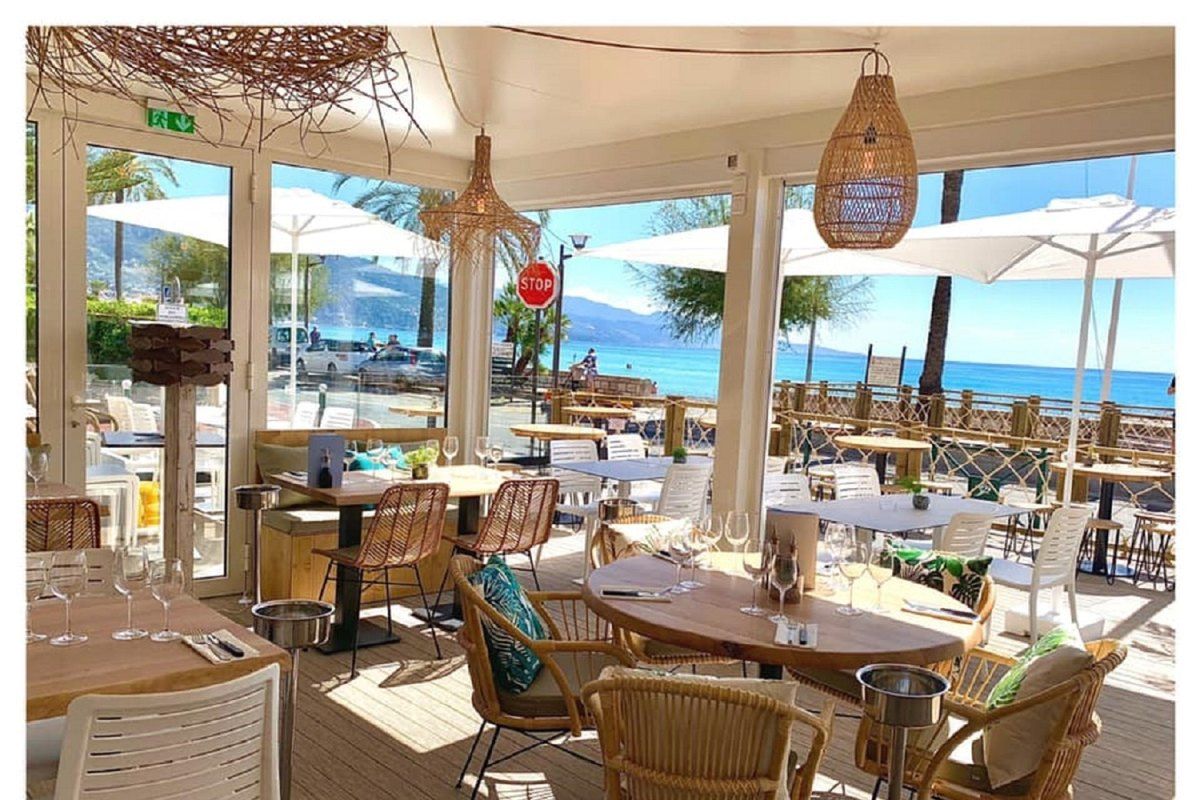 Rattan chairs and wooden tables on the glassed sea-front terrace of Madame Bleue, Roquebrune-Cap-Martin