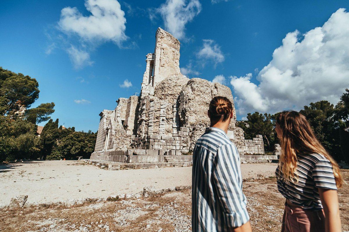 A couple looking up at the Roman Trophée d'Auguste in its park at La Turbie