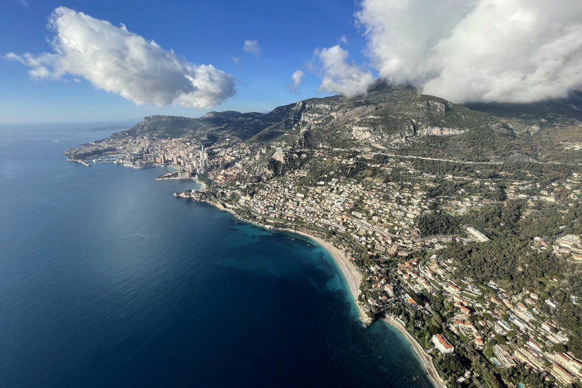 Aerial view along the coast from Roquebrune-Cap-Martin towards Monaco under the mountains, taken on a paragliding flight