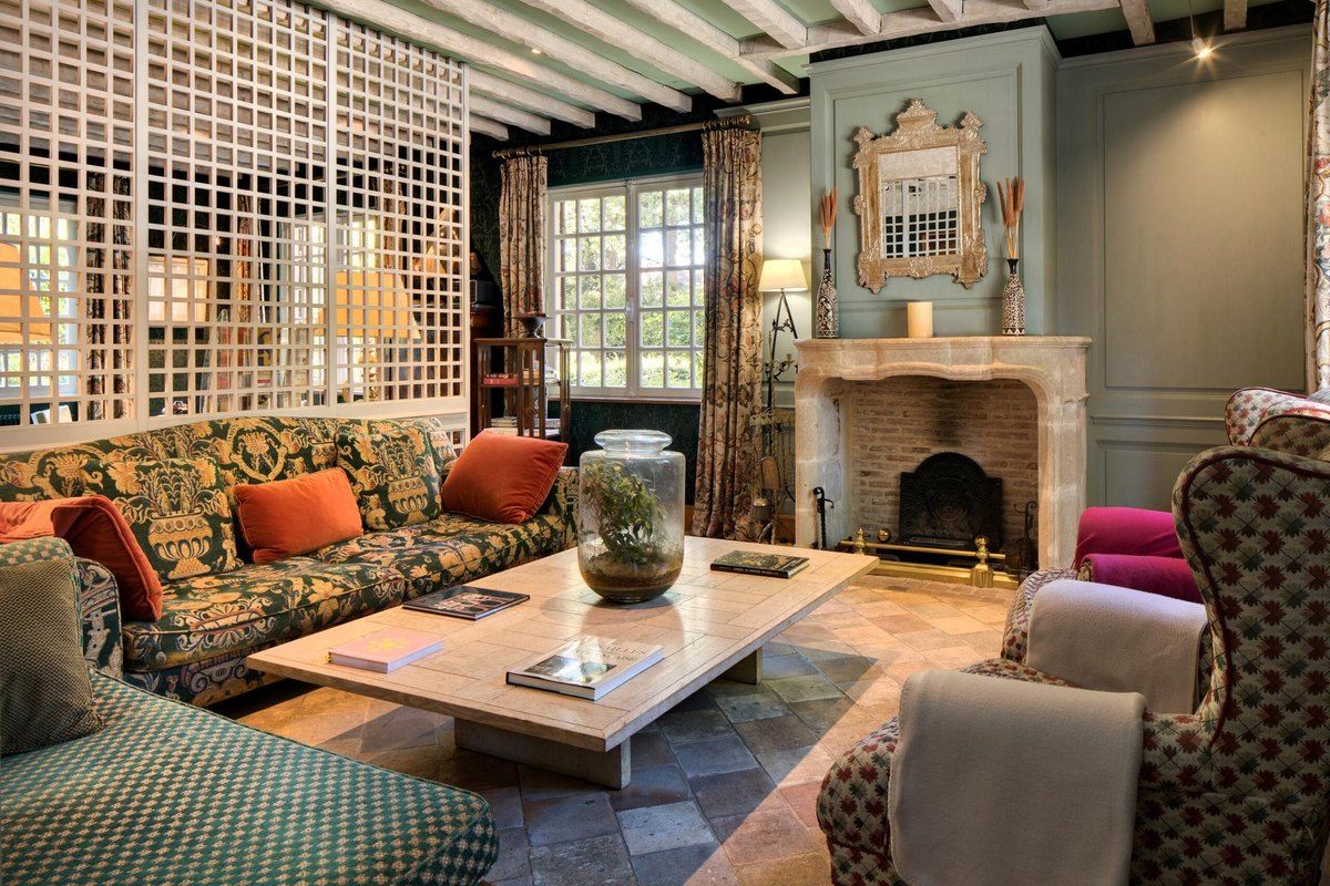 Sofas, armchairs and an open fireplace in the lounge of Cazaudehore at the edge of the forest of Saint-Germain-en-Laye
