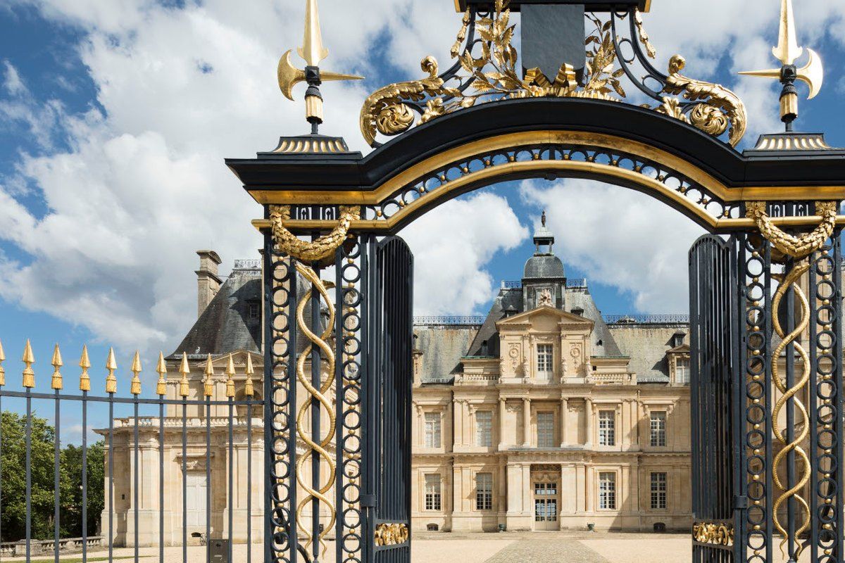 The gilded wrought-iron gate framing the Château de Maisons in Maisons-Laffitte
