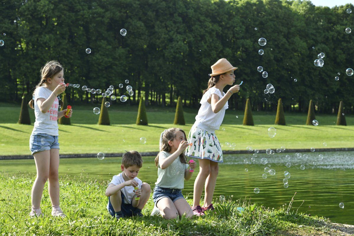 Children blowing soap bubbles beside the water mirror in the Domaine national de Marly