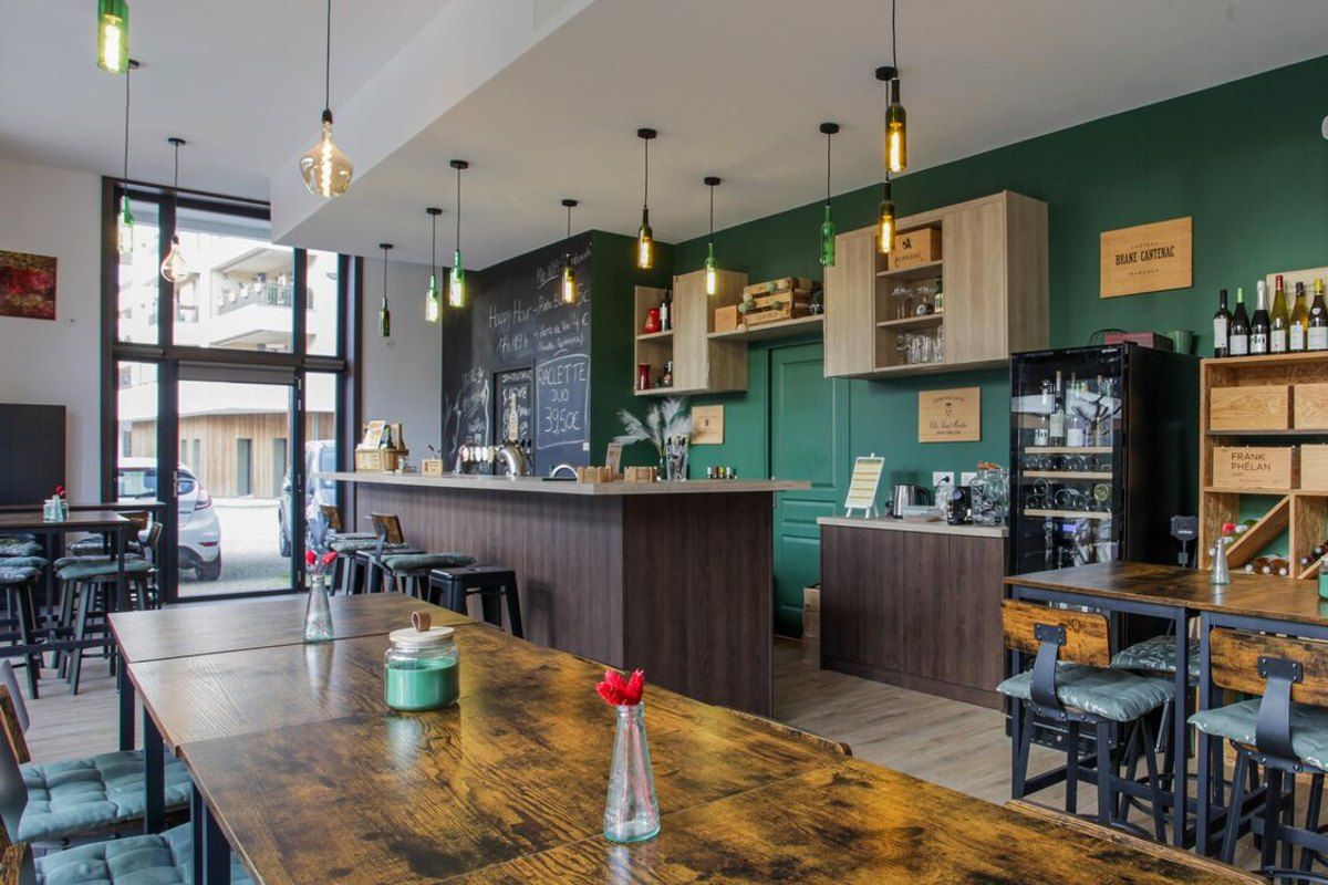 Wooden tables, bar stools and green walls at La Vigne et le Houblon, a wine and craft-beer bar in Saint-Germain-en-Laye