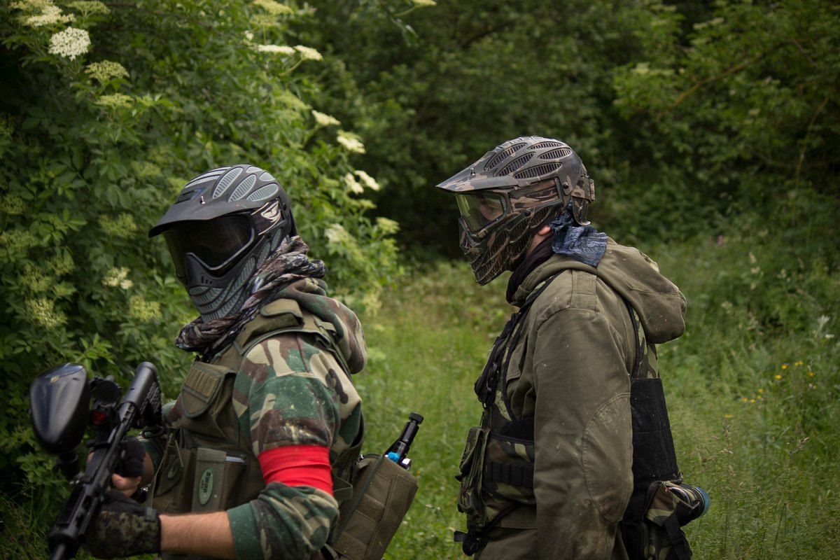 Two masked paintball players in camouflage on a woodland field at Paintball 75, Le Port-Marly