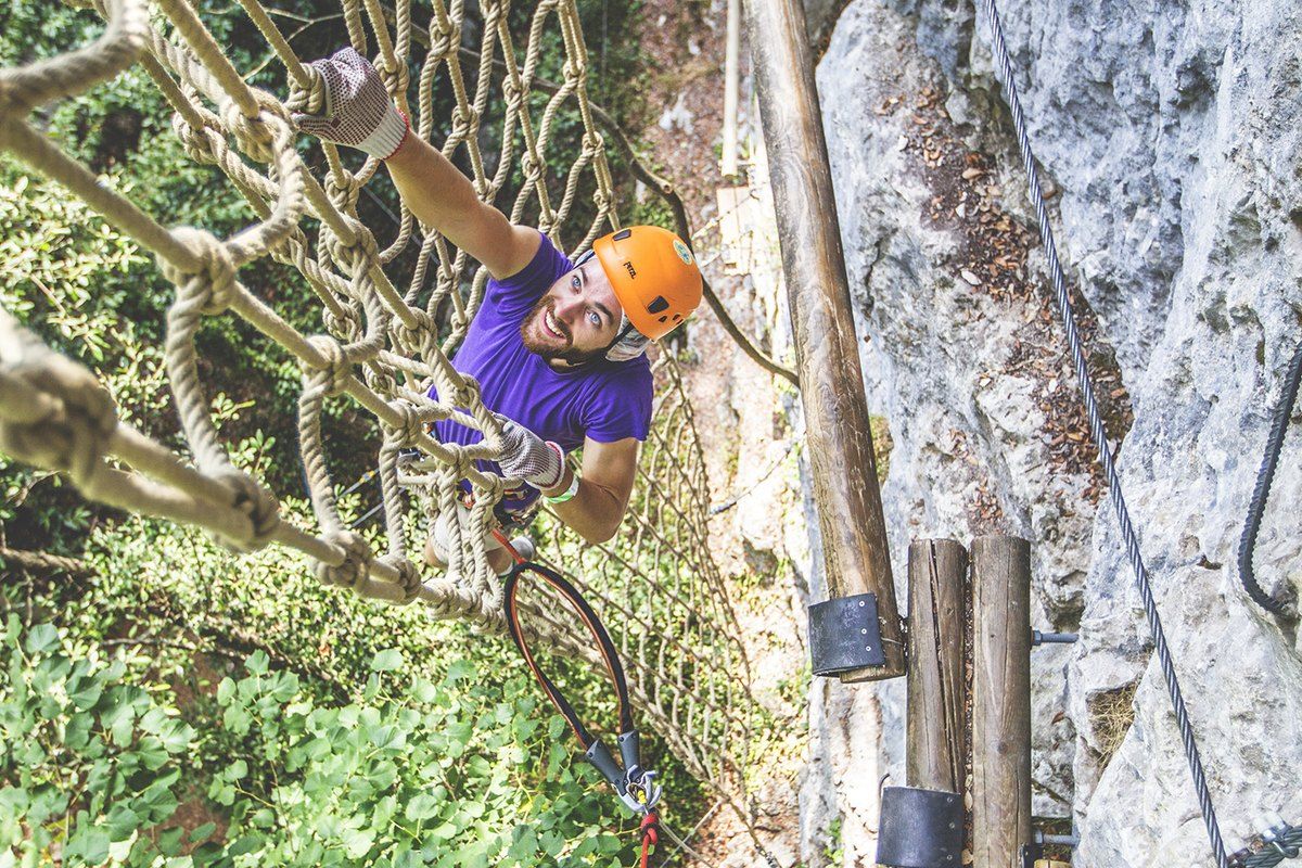 A climber in a harness on the limestone cliff course at Canyon Forest in the Loup valley