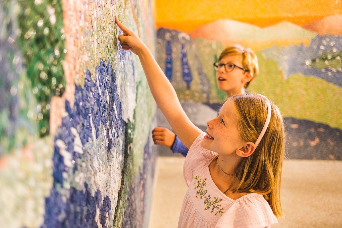 Two children touching Jean-Michel Folon's mosaic inside the Chapelle des Pénitents Blancs in Saint-Paul de Vence