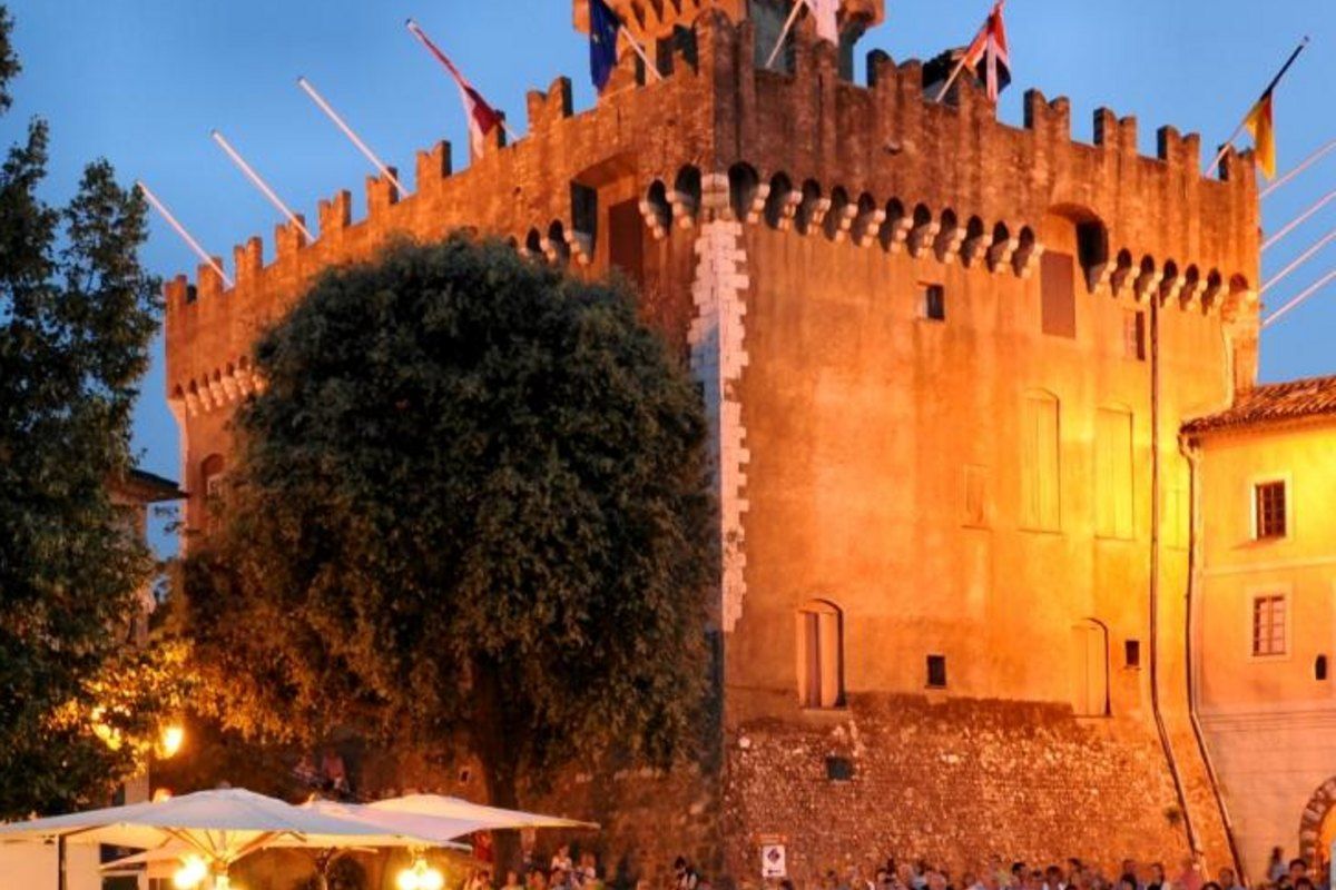 The floodlit Château-Musée Grimaldi above a crowded square in Haut-de-Cagnes at dusk