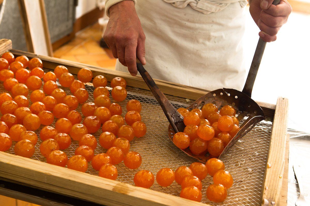 Candied clementines being lifted from a copper pan at the Confiserie Florian in Pont-du-Loup