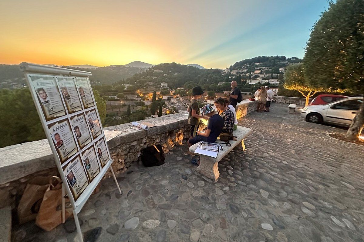 Players gather round the clue board of a live murder-mystery game on a terrace above the hills at dusk
