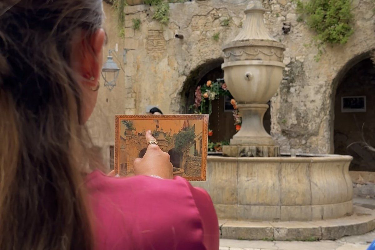 A player studies a clue in a picture frame beside the Grande Fontaine during the Marc Chagall escape game in Saint-Paul de Vence