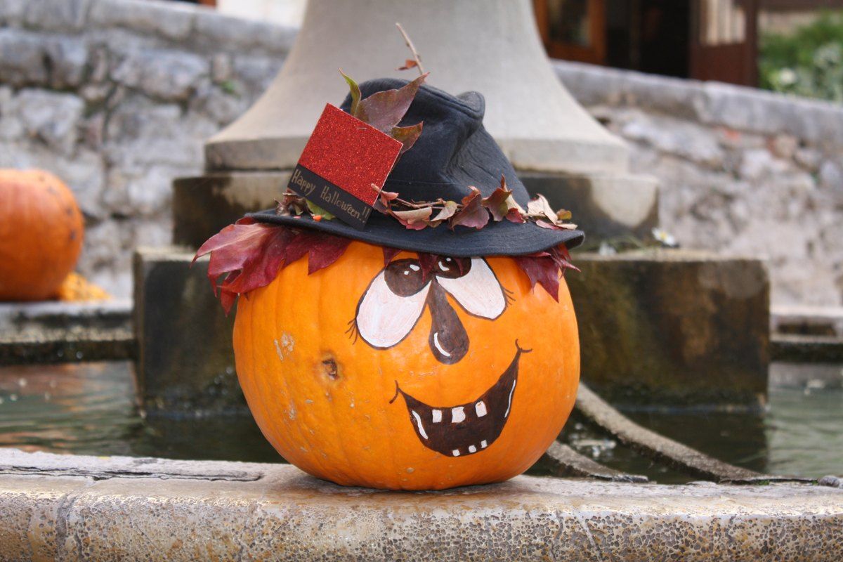 A painted Halloween pumpkin in a witch's hat on the rim of a village fountain in Saint-Paul de Vence