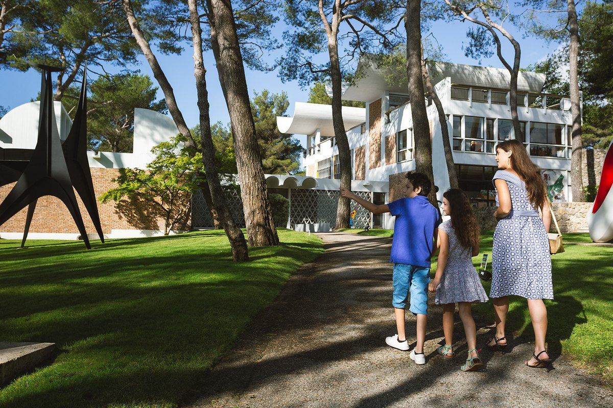 Children and their mother walking through the pine garden of the Fondation Maeght past a Calder sculpture