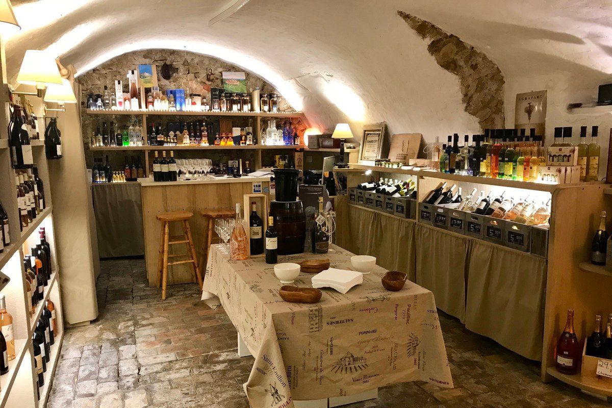 The vaulted 14th-century cellar of La Cave de Saint-Paul, lined with wine shelves