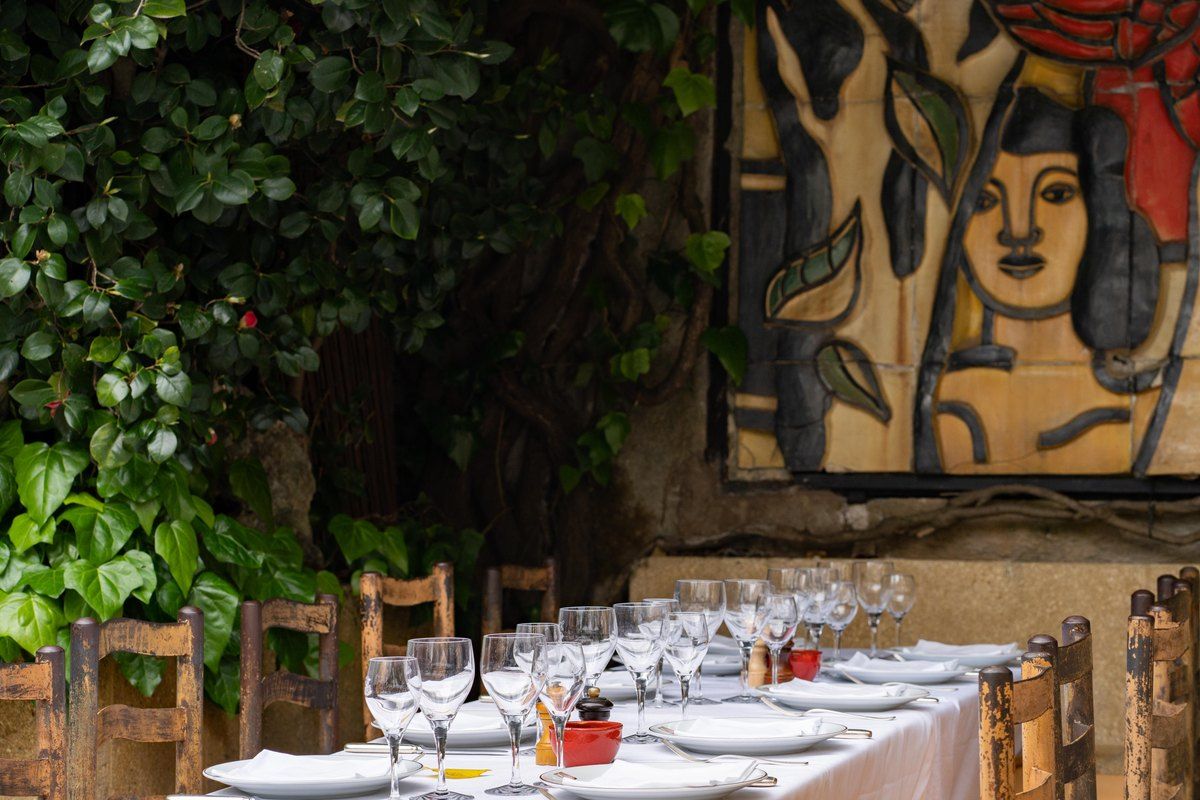 Laid tables on the vine-hung terrace of La Colombe d'Or beneath a large painted mural