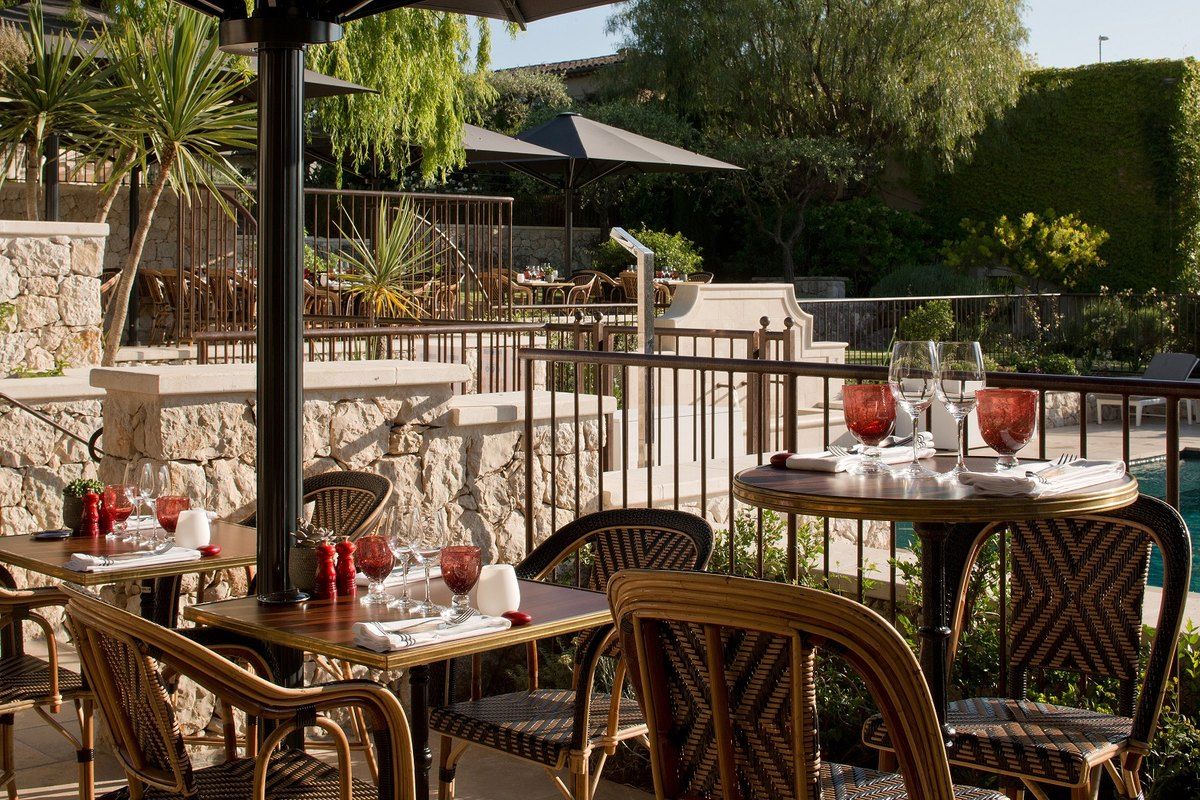 Terrace tables under parasols beside the gardens of the Domaine du Mas de Pierre