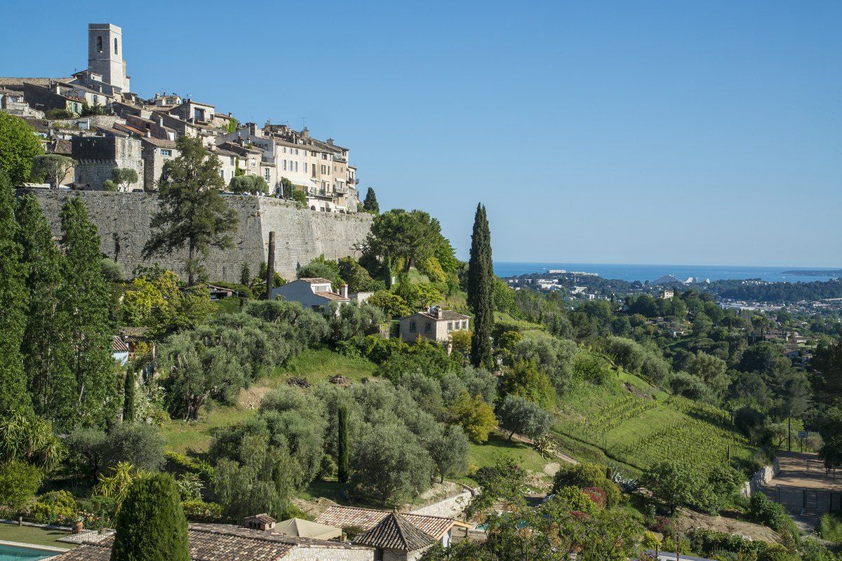 Saint-Paul de Vence on its ridge above vineyards, olive groves and cypresses, with the sea on the horizon