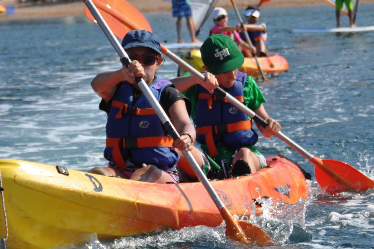 Two children in life jackets paddling a yellow sea kayak off Agay