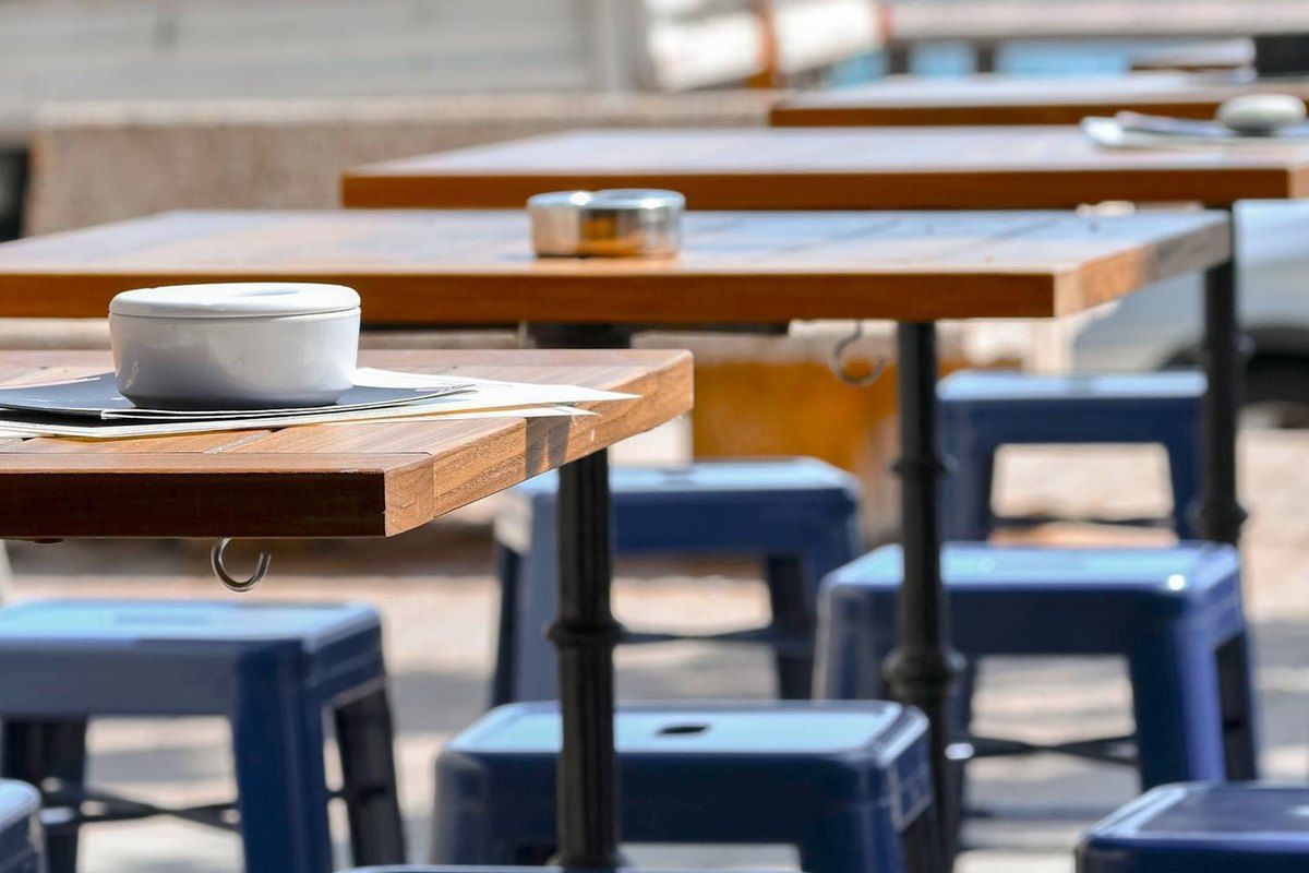 High wooden tables and blue stools on the sea-view terrace of the Café des Bains in Saint-Raphaël