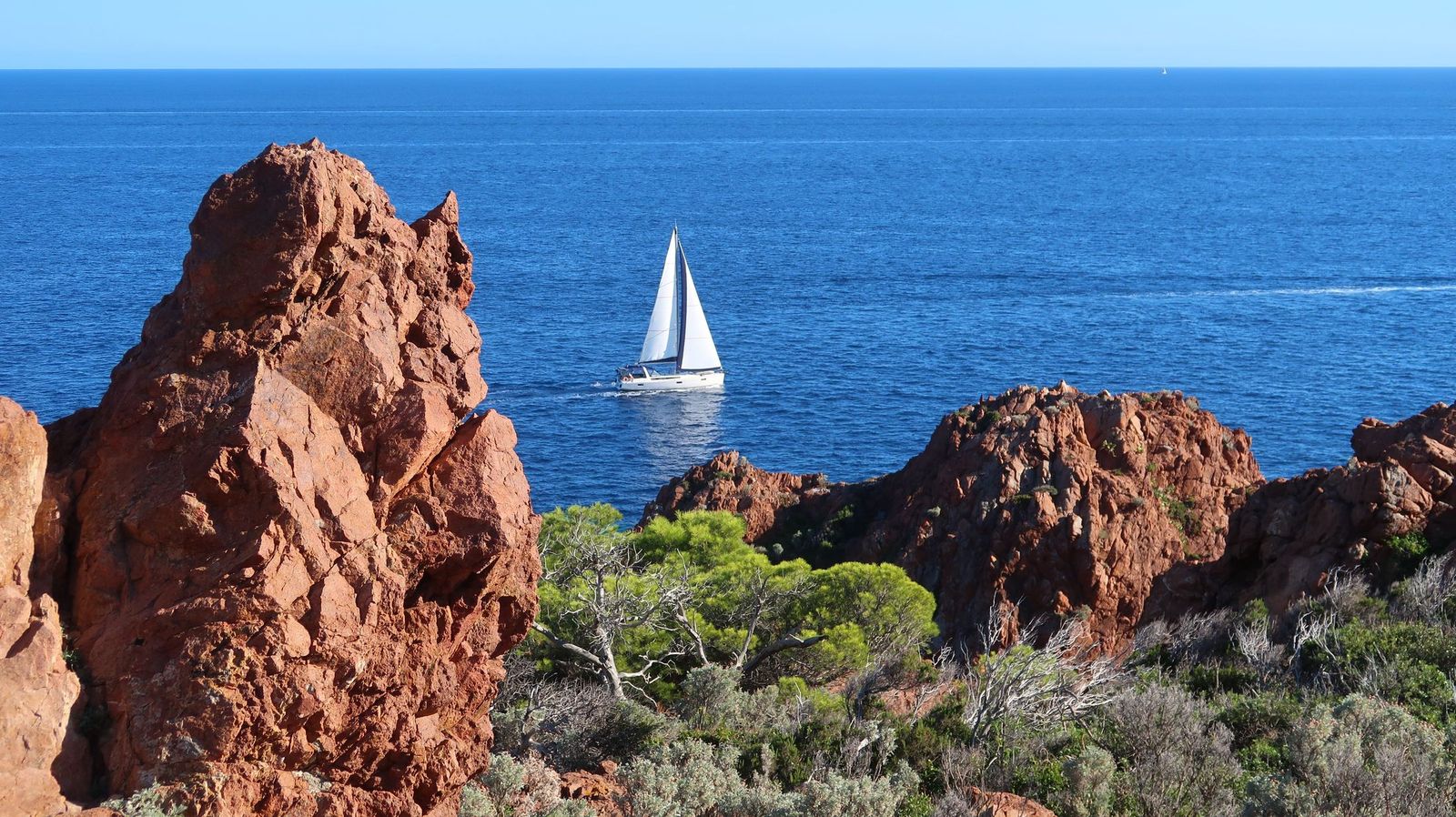 A sailing boat off Cap Dramont and the red rocks of the Esterel