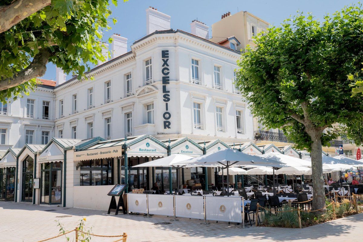 The white Belle Époque façade of the Hôtel Excelsior on the Saint-Raphaël seafront, its terrace under plane trees