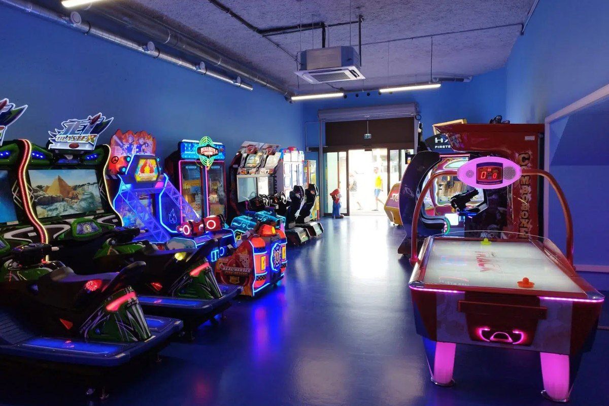 Arcade machines and an air-hockey table in the blue-lit games room of Family's Games on the Saint-Raphaël harbour
