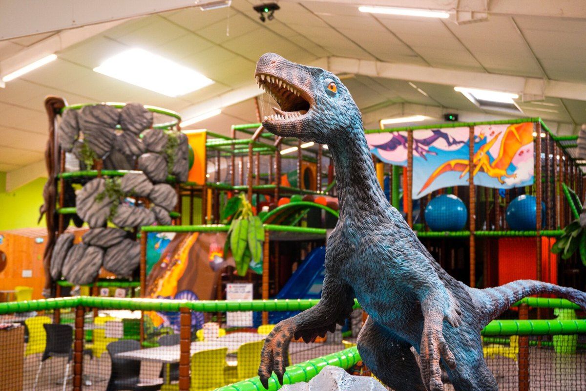 A life-size dinosaur in front of the climbing frames and slides of the Fun City indoor play park in Fréjus