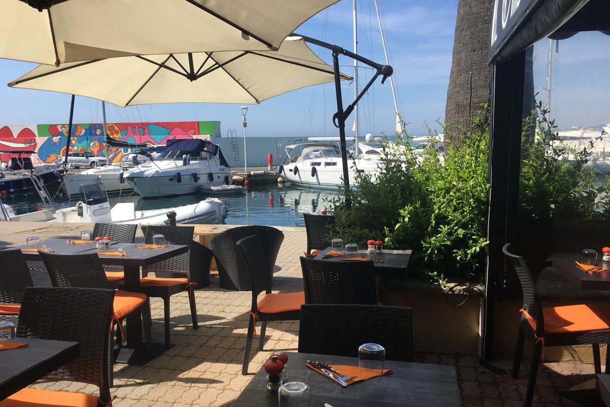 The shaded terrace of L'Obsolète facing the yachts of Port Santa Lucia