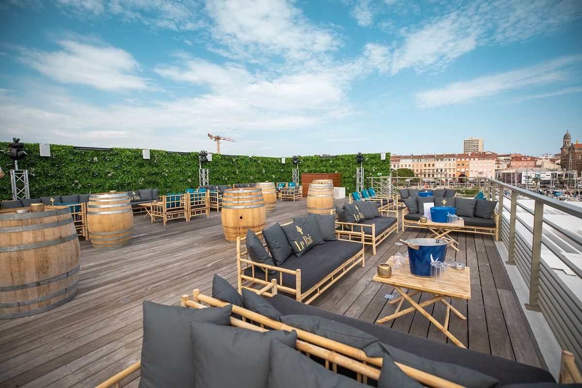 The rooftop lounge deck of Le Baïa above the Old Port of Saint-Raphaël, with sofas and wine-barrel tables
