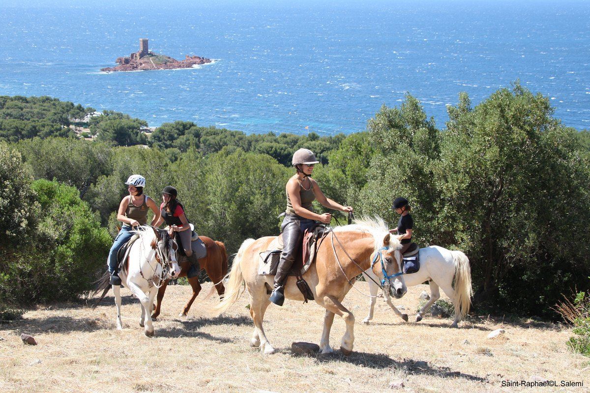 Riders and ponies from Les 3 Fers on a scrubland track above the sea at Le Dramont, the Île d'Or in the distance