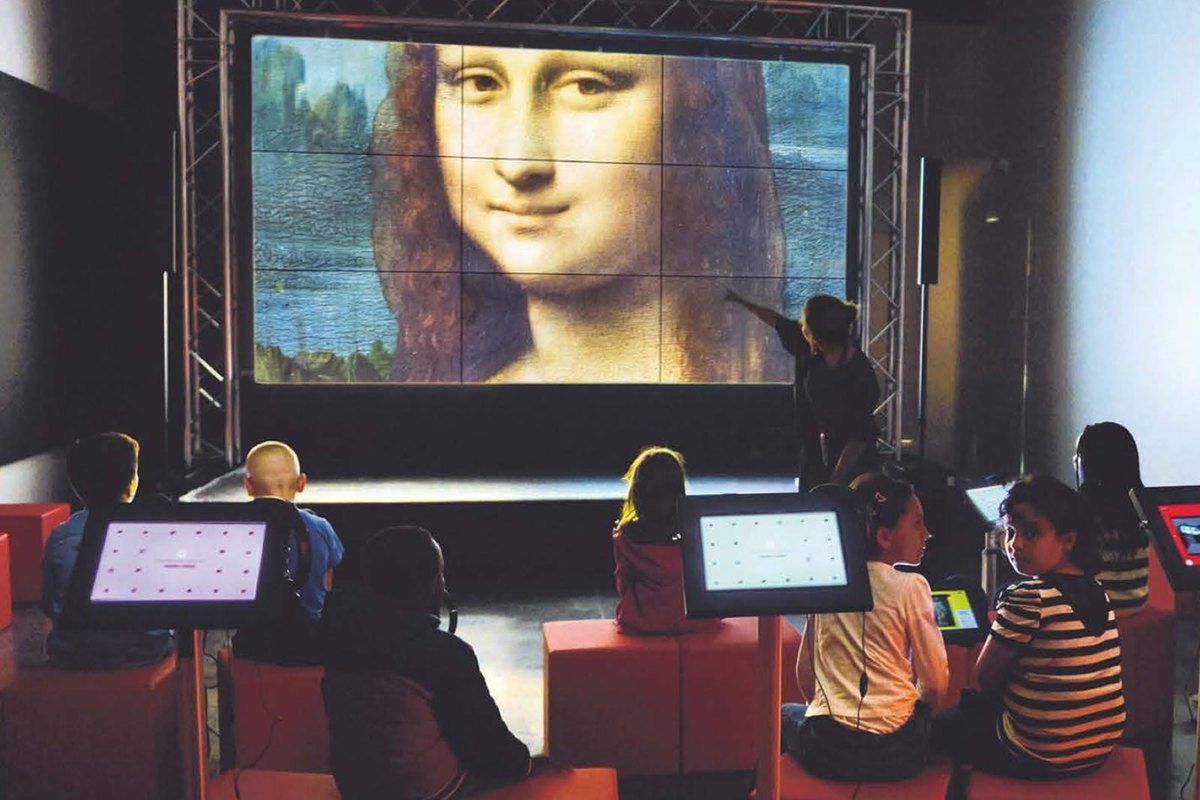 Children with tablets in front of the giant screen at the Micro-Folie digital museum, showing the Mona Lisa