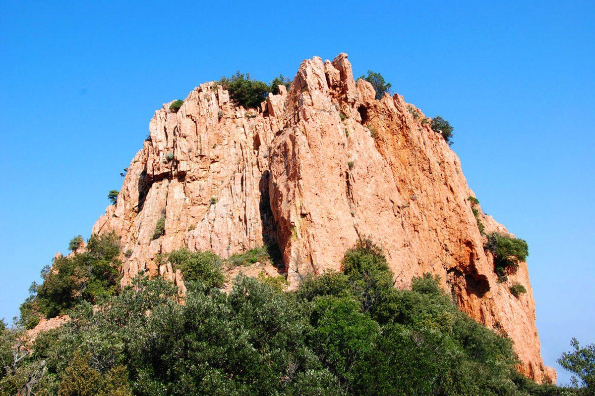 The red pinnacle of the Dent de l'Ours rising out of green scrub in the Estérel massif