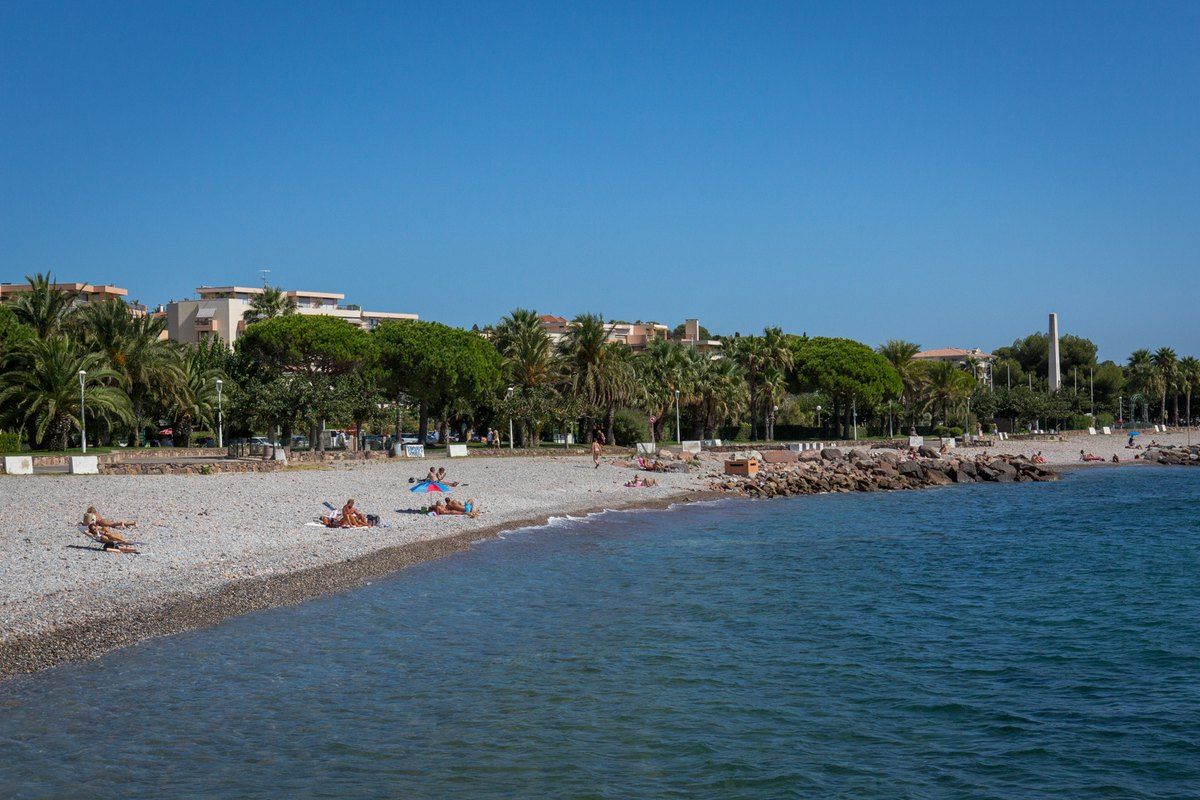Plage Beau Rivage in Saint-Raphaël, a long pebble beach backed by palms and pines