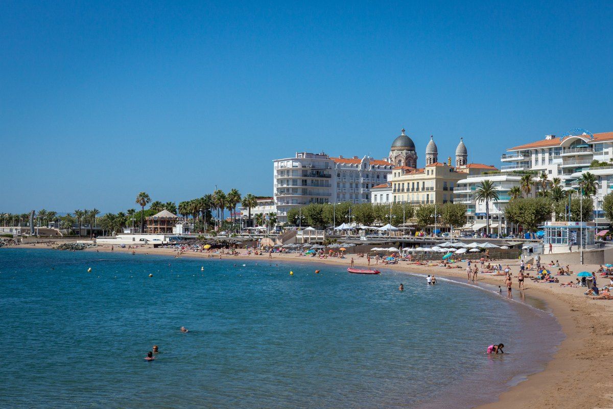 The sandy curve of Plage du Veillat in Saint-Raphaël, with the domes of Notre-Dame-de-la-Victoire and the seafront hotels behind