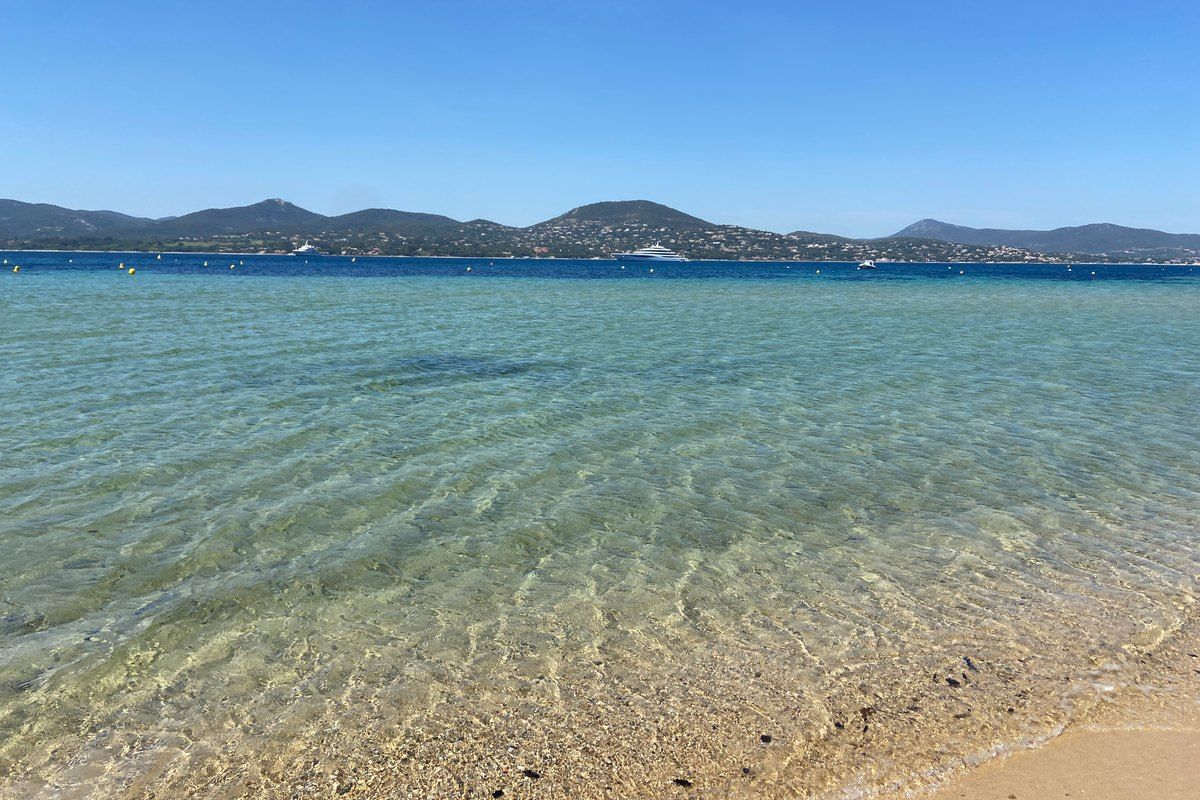 Clear shallow water at the Bouillabaisse beach, looking across the gulf to the Maures hills