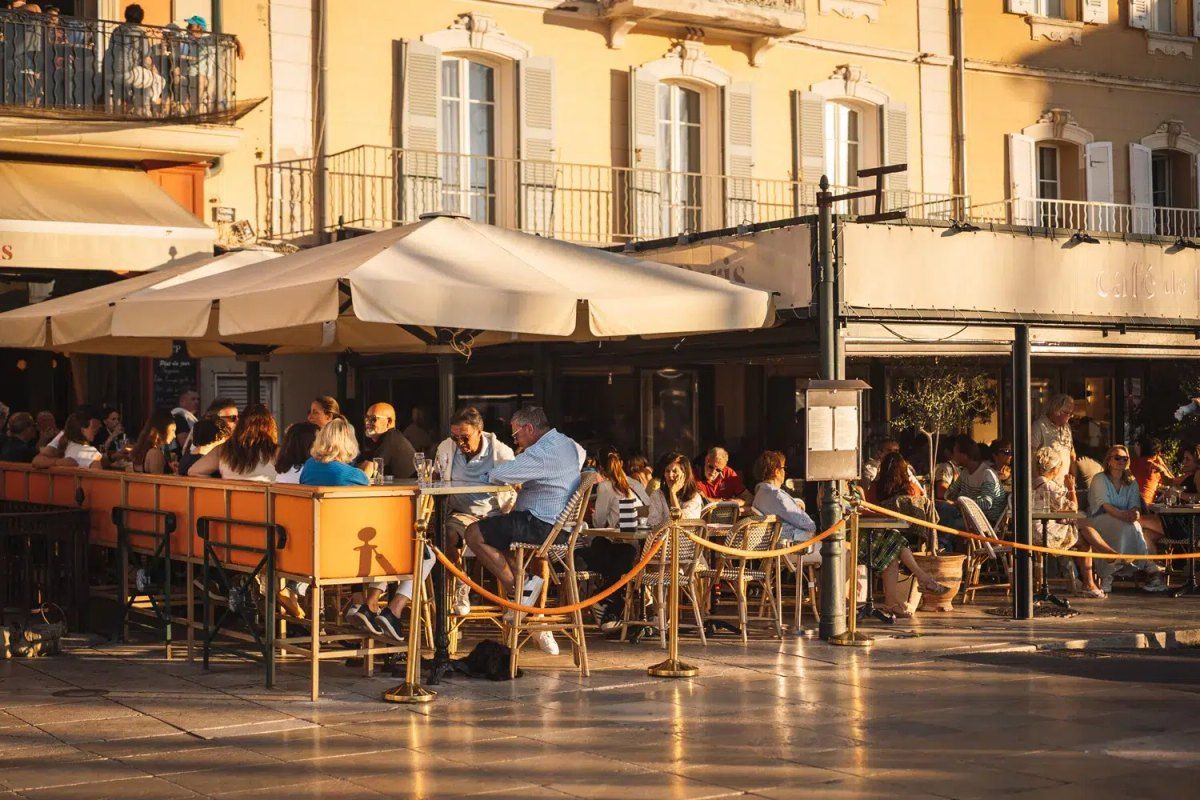 The busy terrace of the Café de Paris on the old port of Saint-Tropez in late-afternoon light