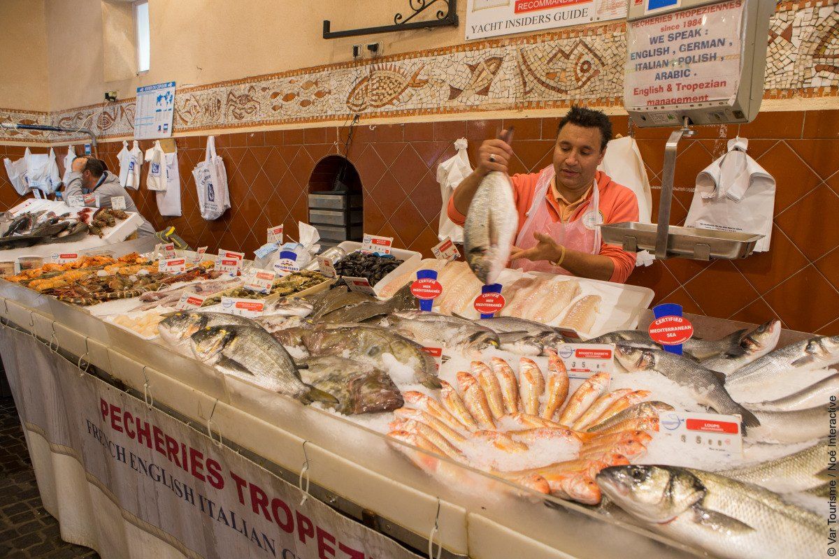 A fishmonger behind marble slabs of the day's catch at the covered fish market in Saint-Tropez