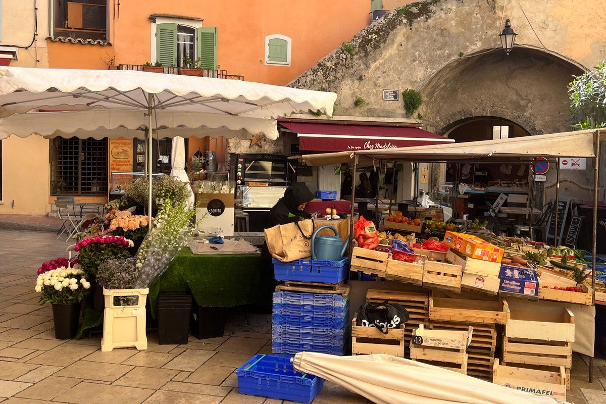 Fruit, vegetable and flower stalls under the arch of the Place aux Herbes market in Saint-Tropez