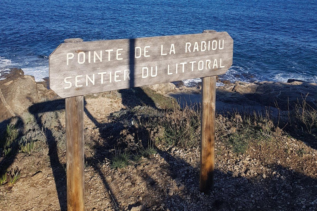 A wooden 'Pointe de la Rabiou – Sentier du Littoral' sign on the rocks above the sea, Saint-Tropez