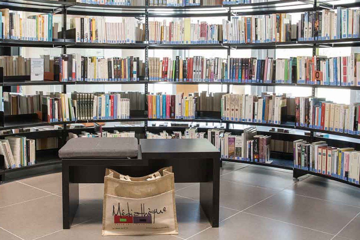 Curved shelves of books around a reading table at the Médiathèque Jehanne Arnaud in Sainte-Maxime