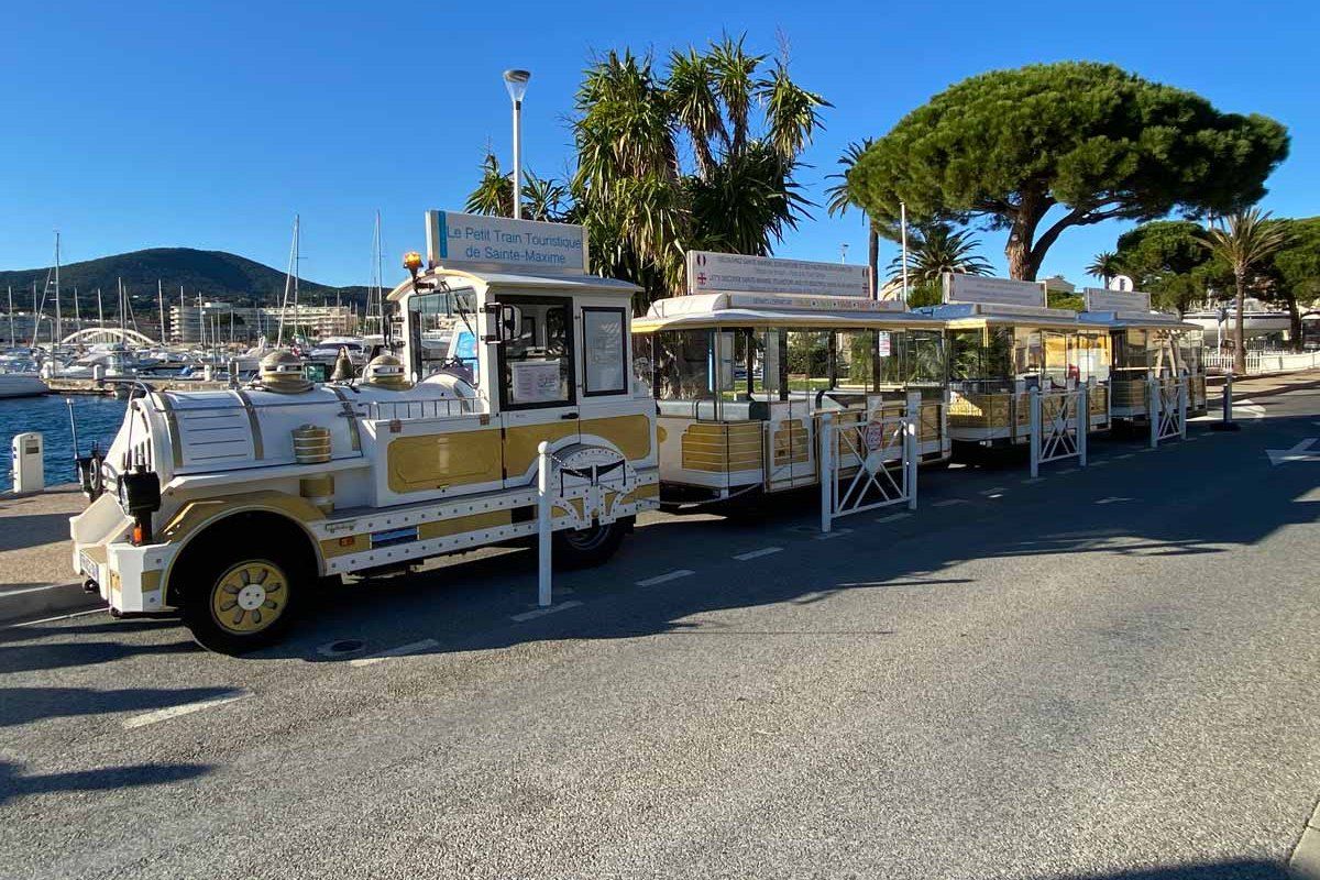 The cream-and-gold Petit Train de Sainte-Maxime on the harbour road under pines