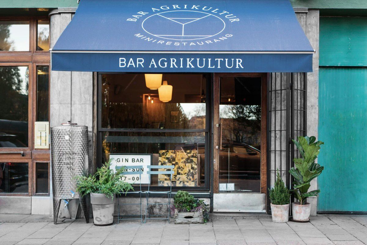 The blue awning and lit window of Bar Agrikultur on Skånegatan, by Nytorget on Södermalm