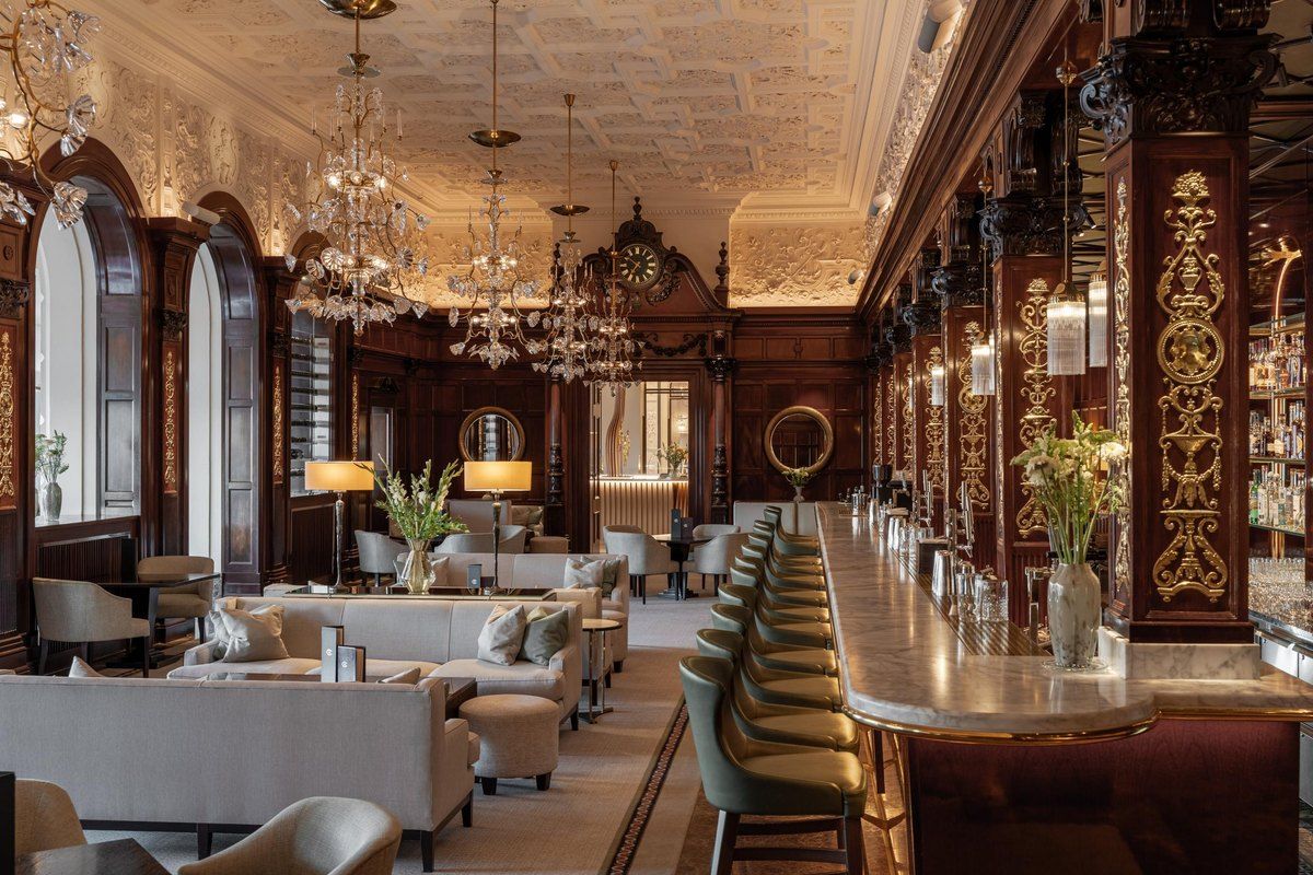The long, chandelier-lit Cadierbaren at Grand Hôtel with its dark carved panelling, arched windows and green velvet stools