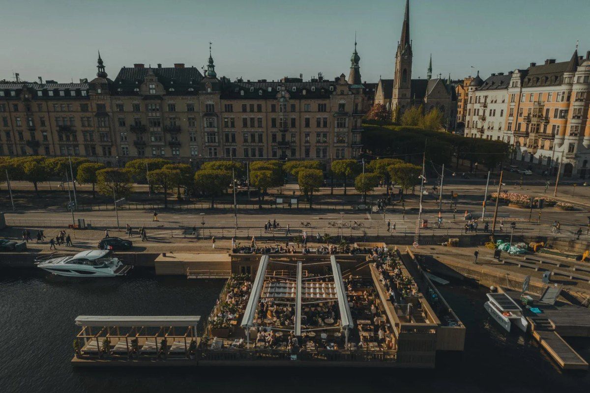 Strandbryggan's floating terrace seen from above, with the façades and church spire of Strandvägen behind