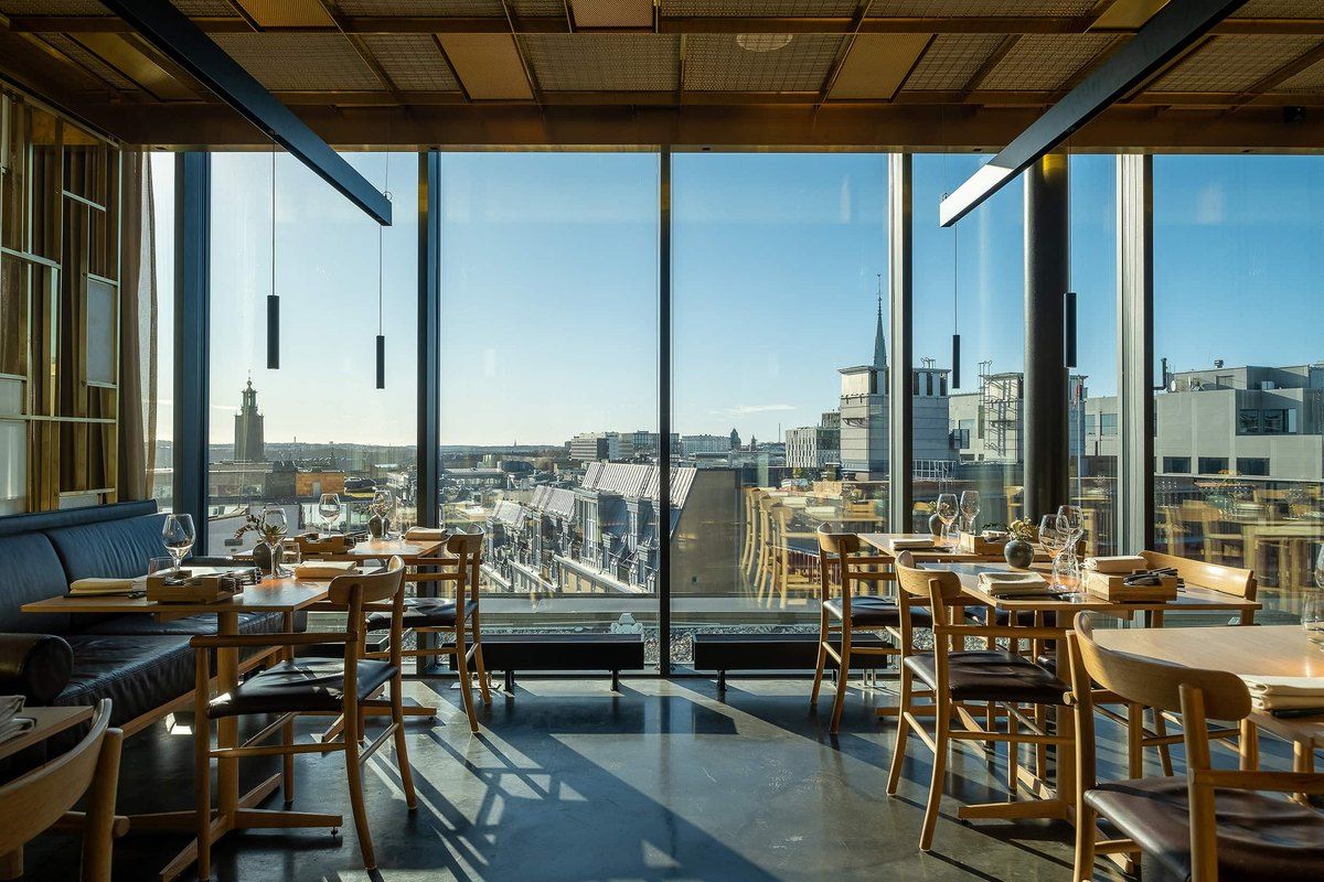 The TAK bar and dining room behind floor-to-ceiling windows, with the rooftops and spires of central Stockholm beyond