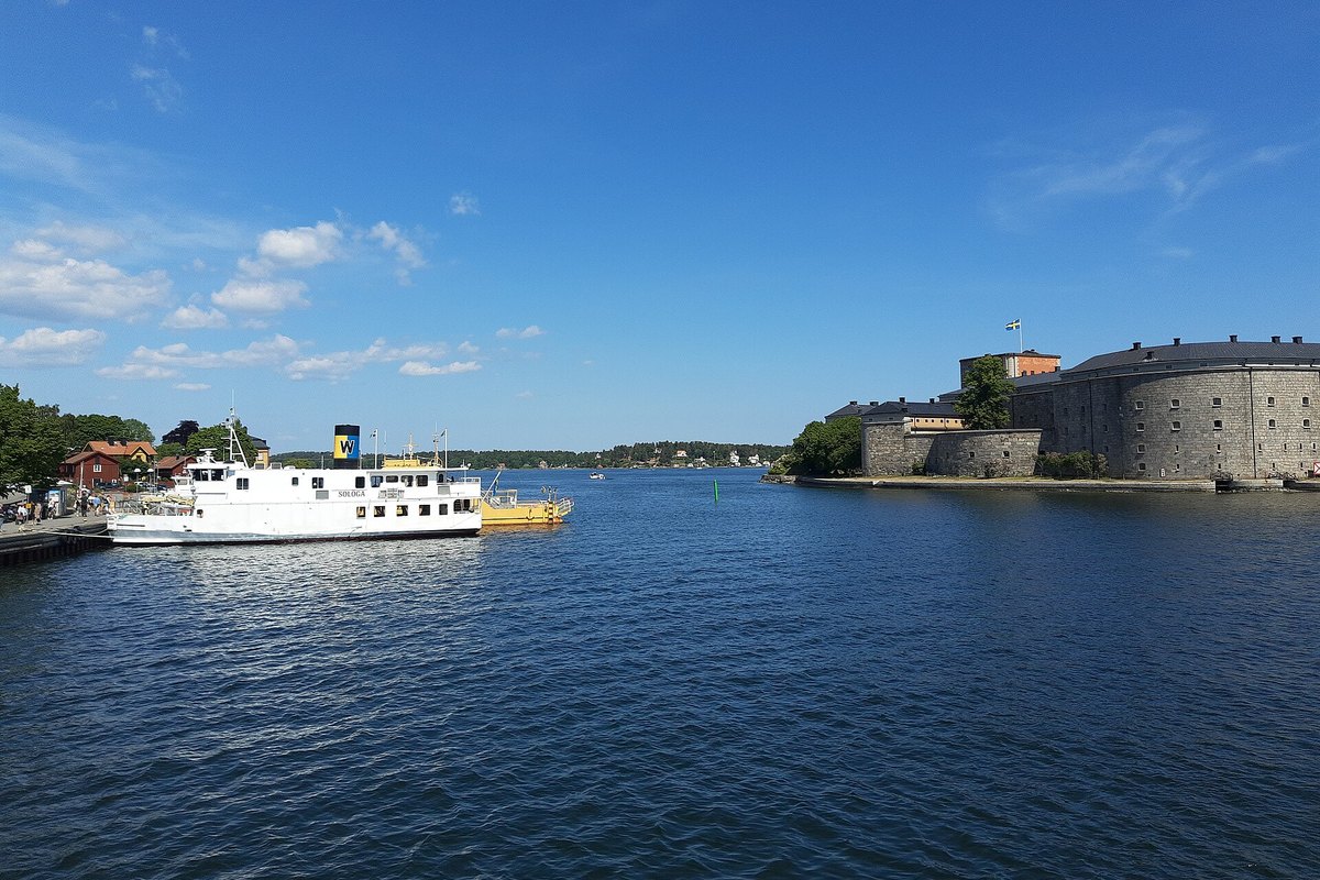 A white archipelago boat crossing the sound in front of Vaxholm fortress