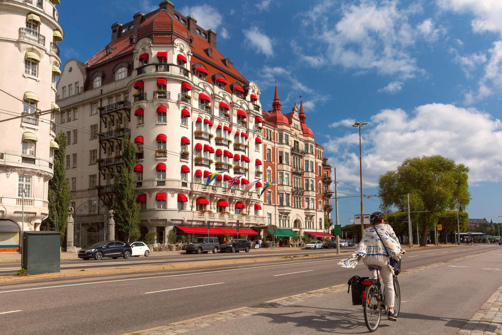 A cyclist passing the grand buildings with red awnings on Strandvägen